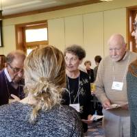 Older and younger people stand around a table